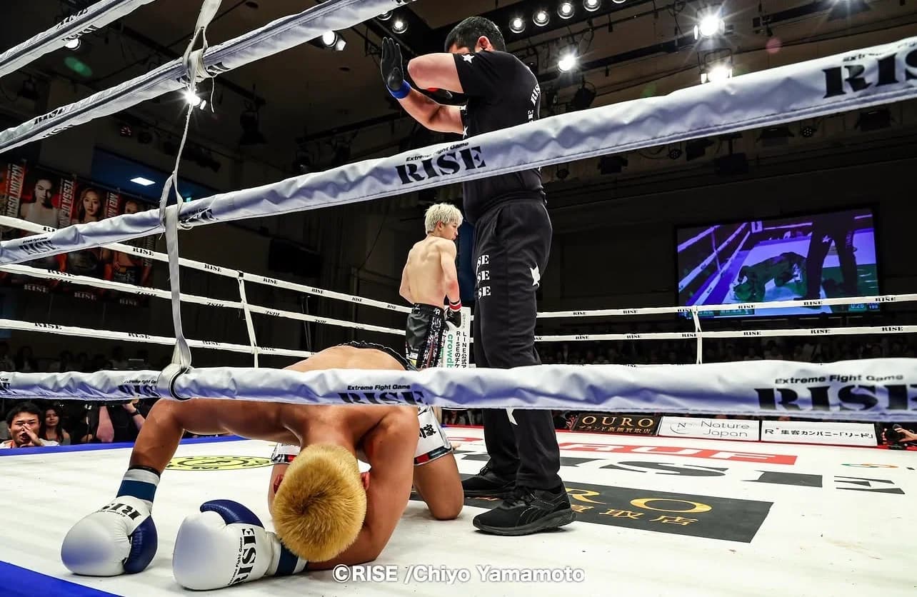 RISEのリング上で試合が終わり、マットに崩れ落ちる選手と、それを制止するために手を上げるレフェリーの様子
